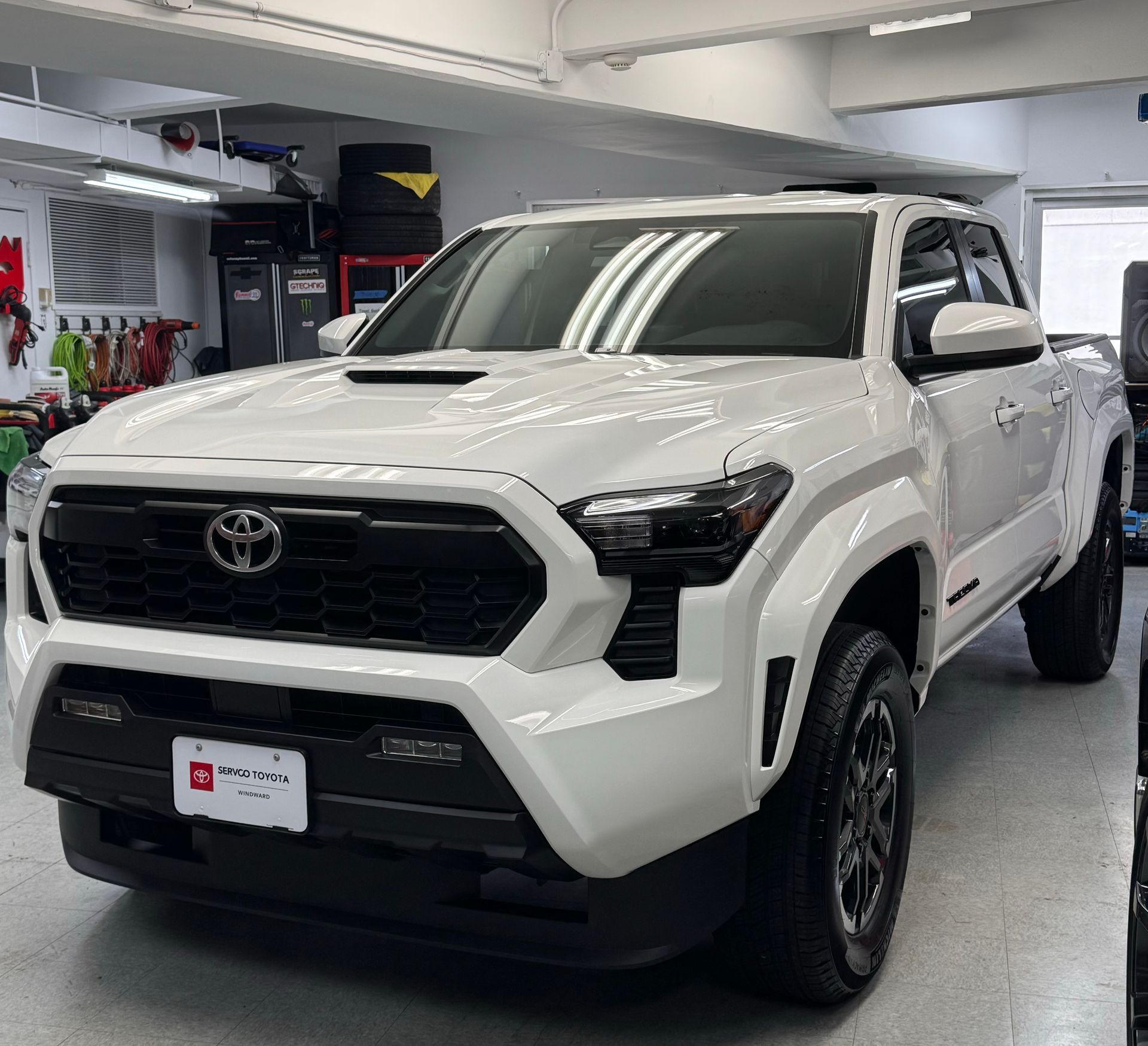 A white toyota tacoma is parked in a garage.