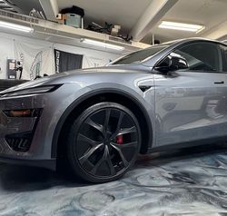 A close up of the front wheel of a black sports car.