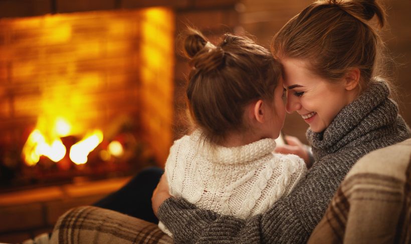 mother and daughter in Massachusetts enjoying a lit fireplace in their home.