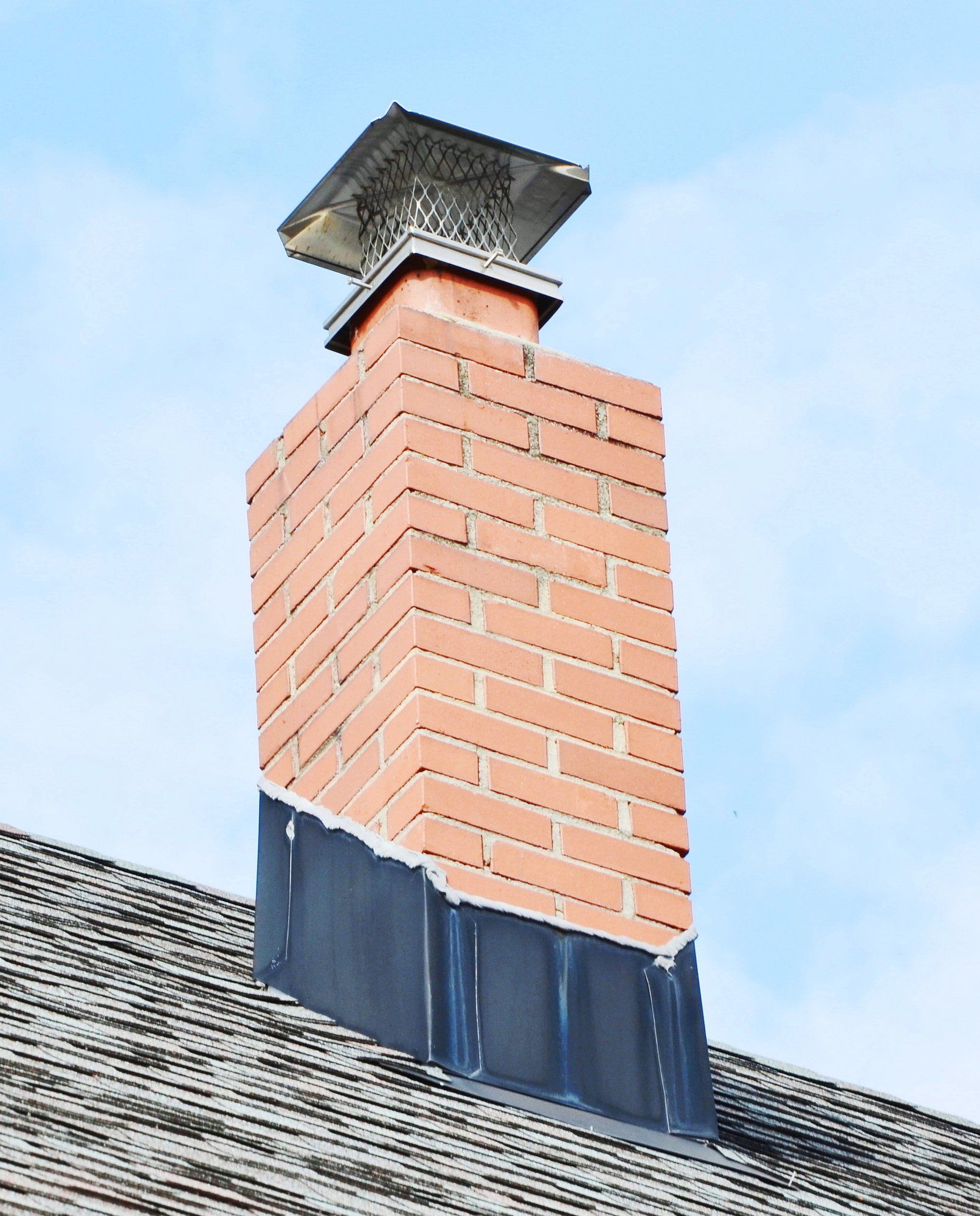 brick chimney with stainless steel chimney cap and new chimney flashing in Waltham MA