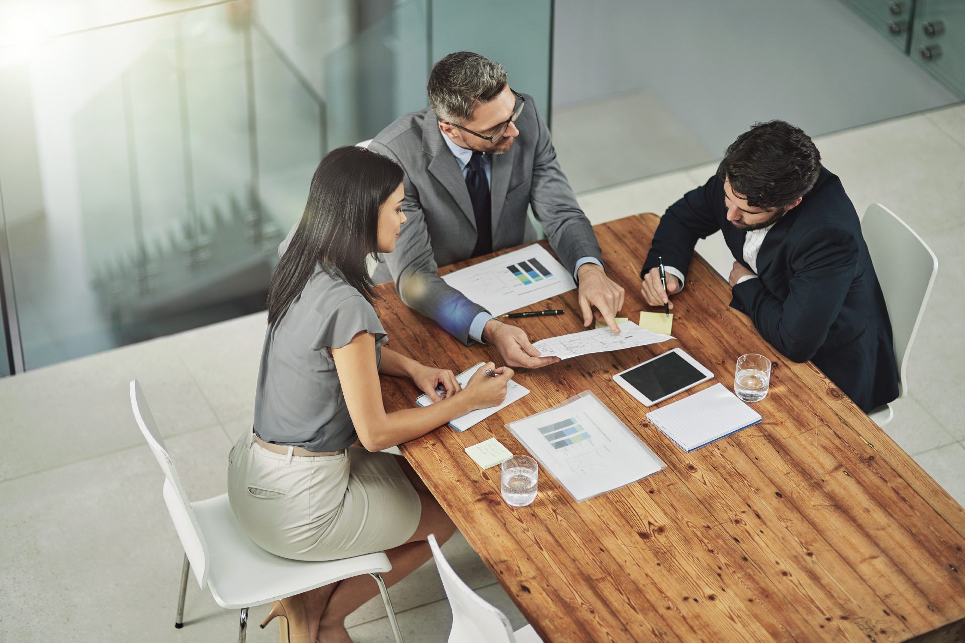 A group of people are sitting around a wooden table having a meeting.