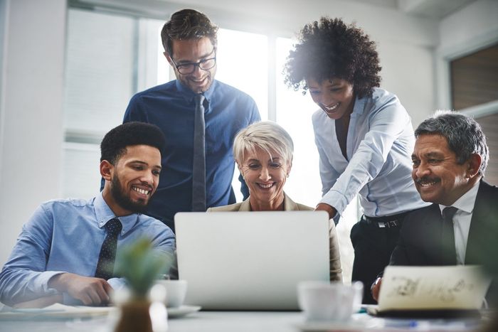 A group of business people are looking at a laptop computer.
