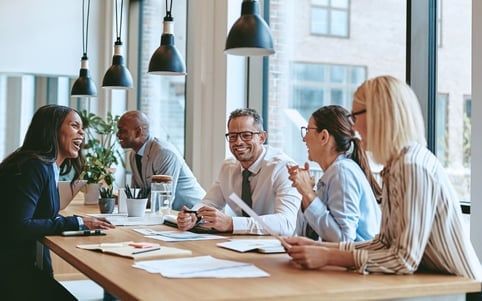 A group of people are sitting around a table having a meeting.