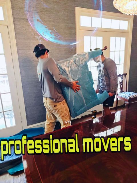 Two men unpacking boxes in a living room. One man holds the box lid; the other lifts a box.