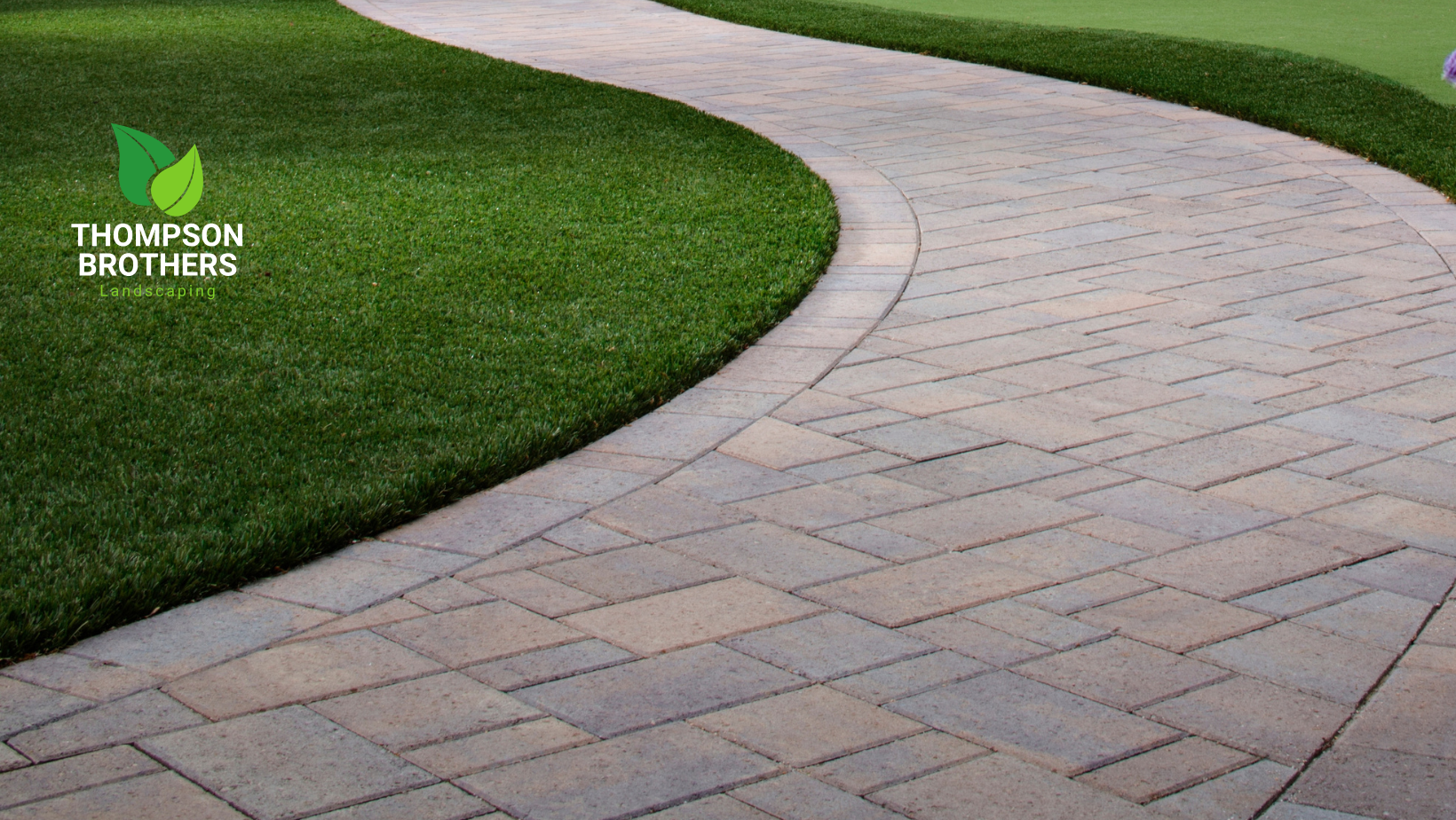 Stone path curving through green grass, bordered by a dark line.