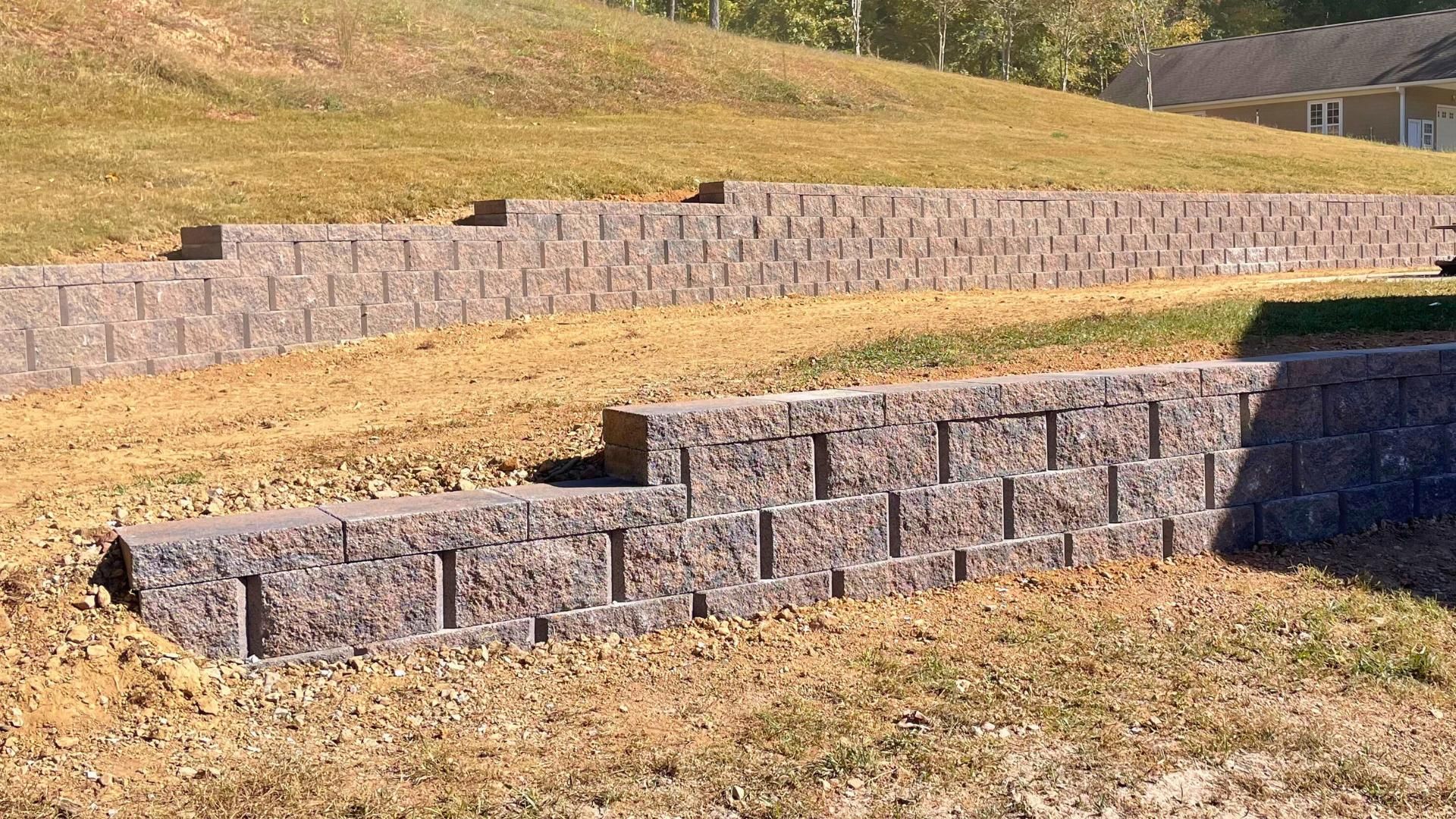 A stone wall is sitting in the middle of a grassy field.