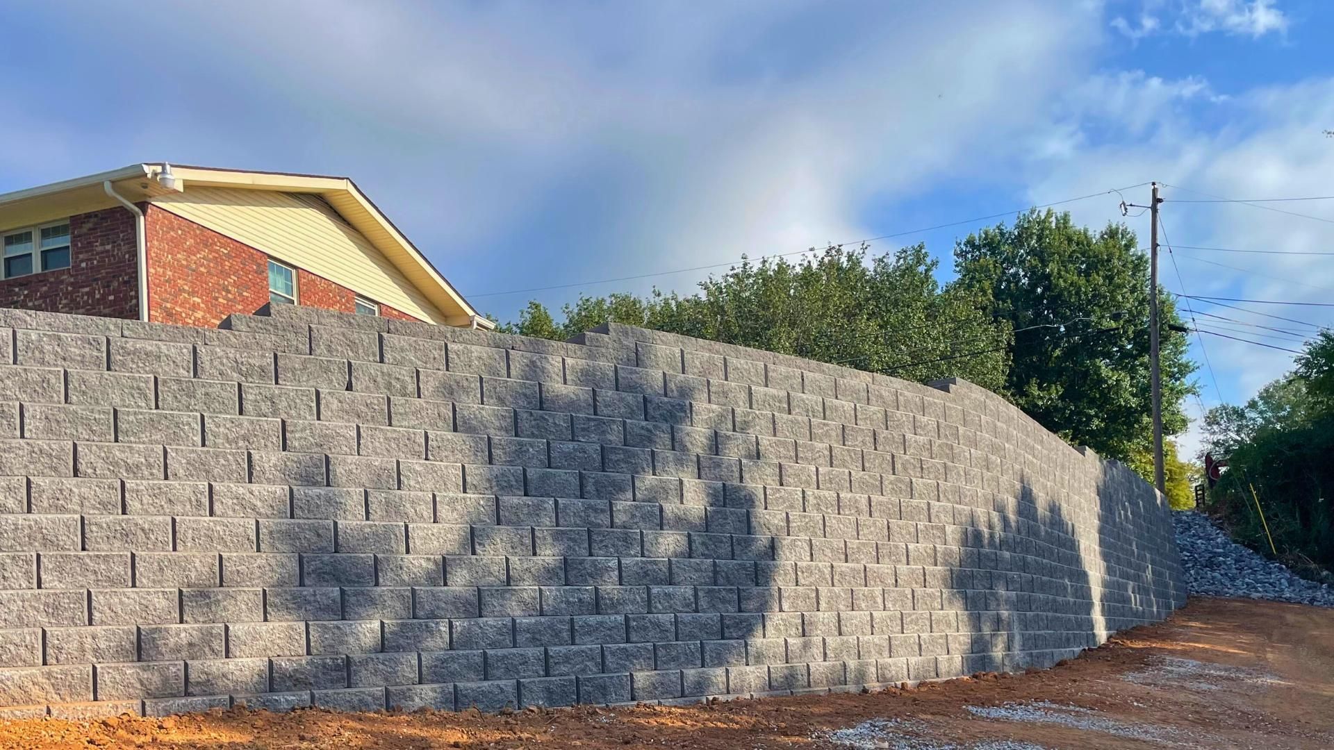 A large brick wall is being built in front of a brick house.