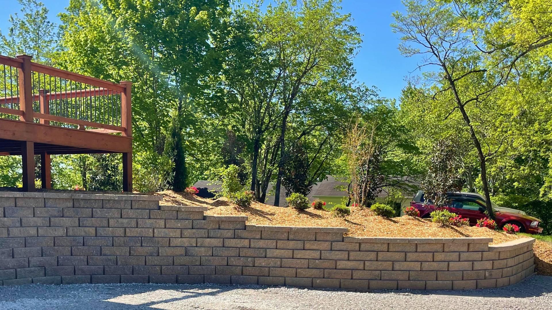 A brick wall with a wooden deck in the background surrounded by trees.