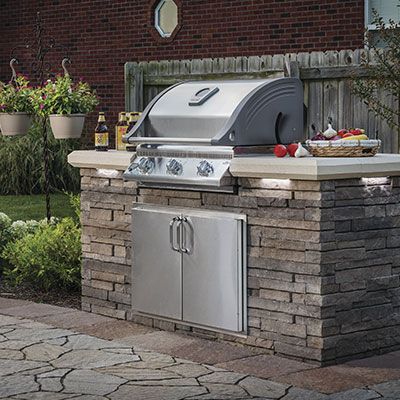 A stainless steel grill is built into a brick wall.