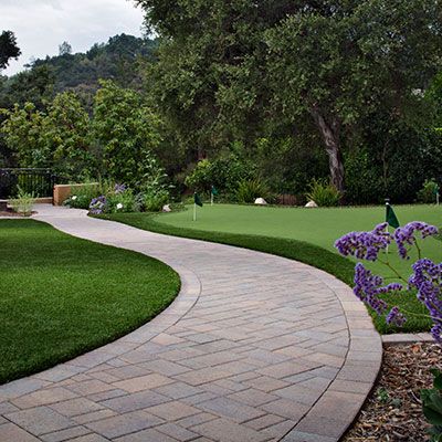 A brick walkway leading to a green golf course.