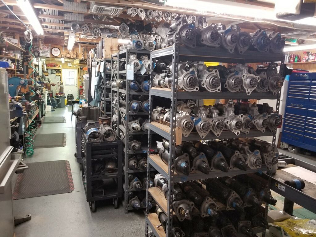 Shelves filled with automotive starters in a cluttered workshop.