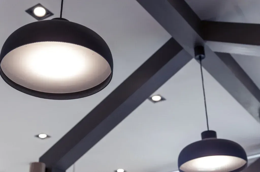 Red and blue electrical wires with yellow connectors, on a roll of yellow electrical tape, against a metallic surface.