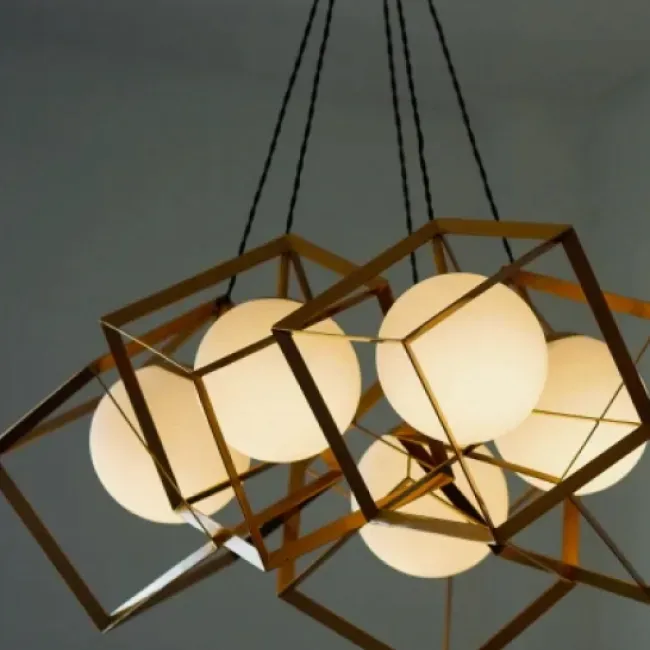 An electrician tests an exposed electrical outlet with a multimeter. They wear gloves and a reflective vest indoors.