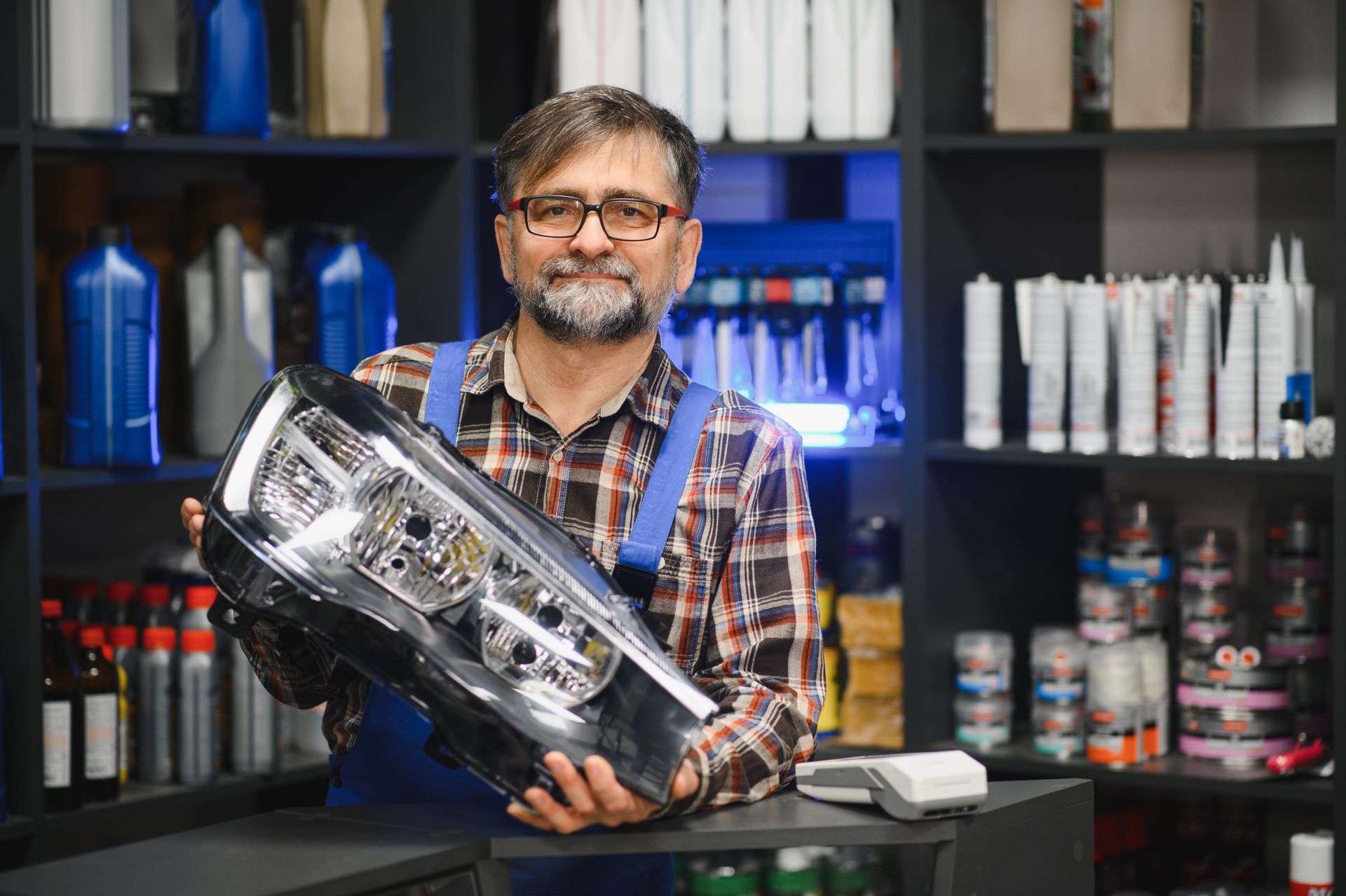 Salesman holding headlight in auto parts store. Salesman holding headlight in auto parts store.
