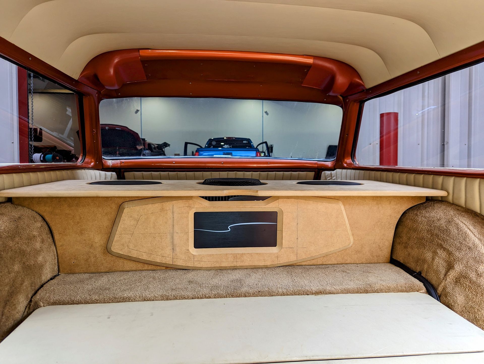 The back of a car with a wooden shelf and a screen on it.