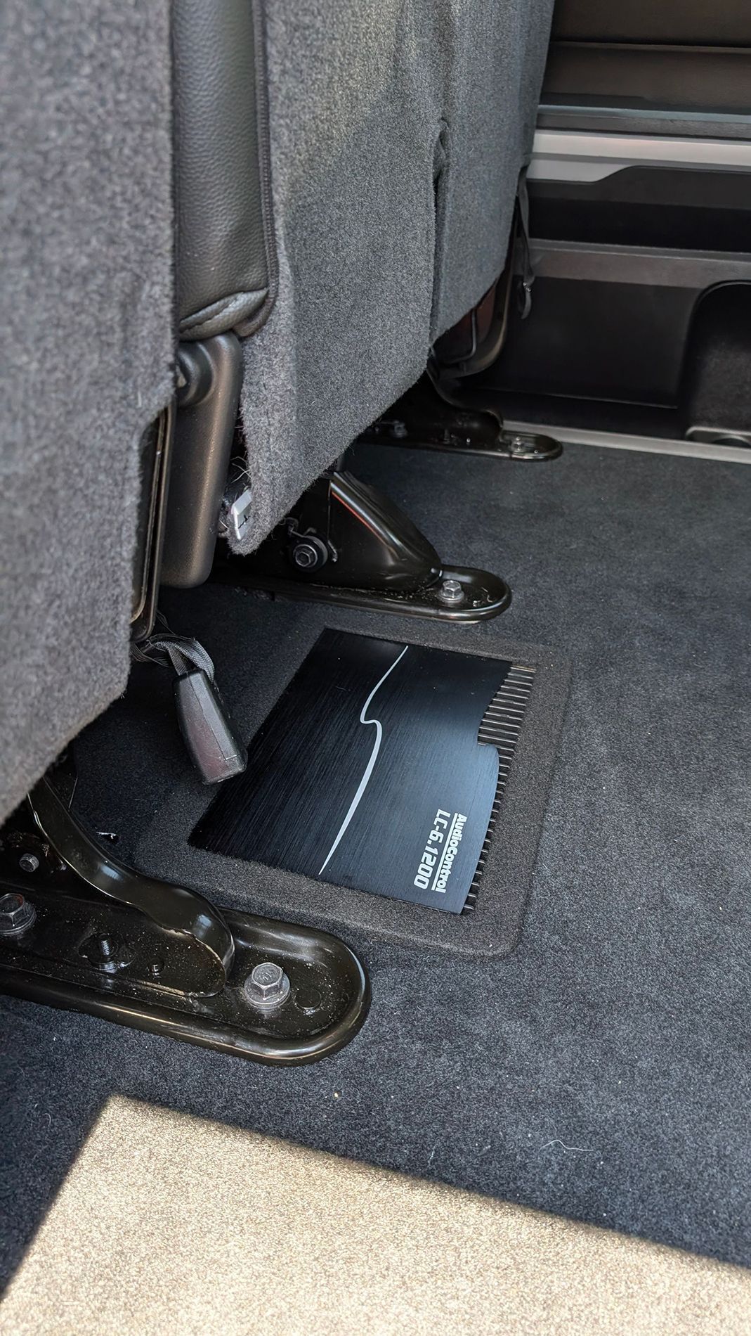 The back seat of a car with a black mat underneath it.