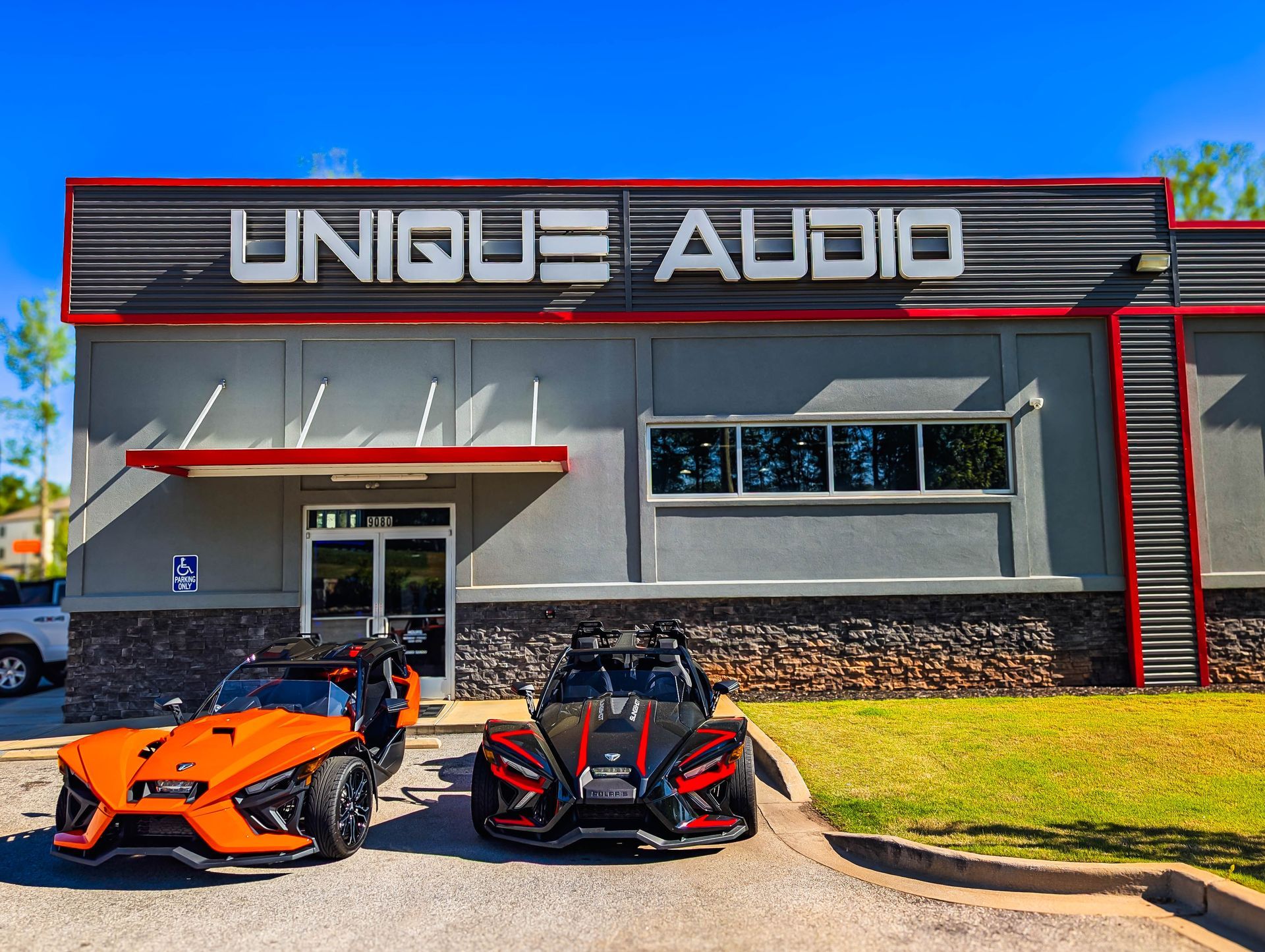 Two motorcycles are parked in front of a building that says unique audio