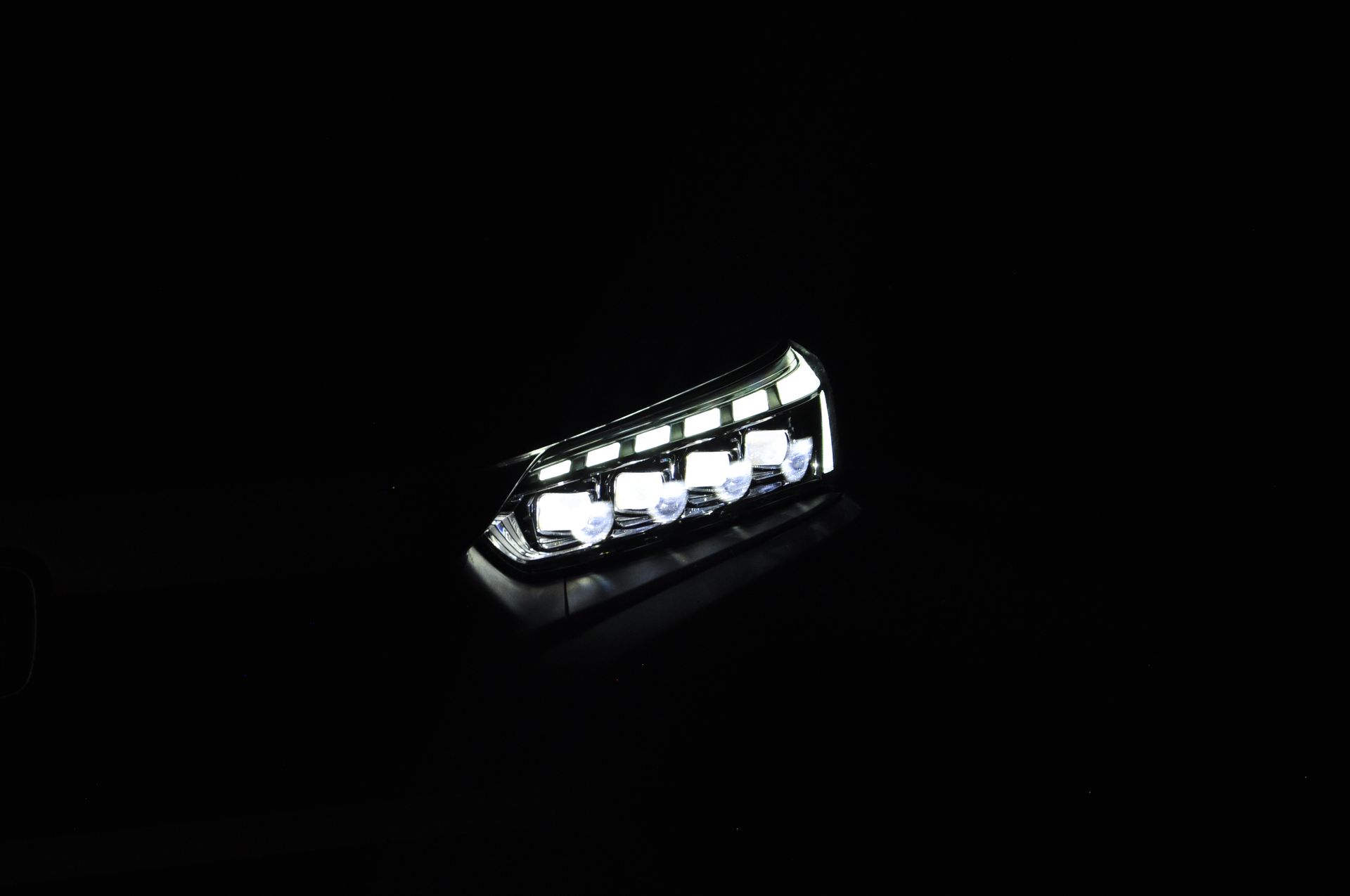 A close up of a car headlight on a black background.