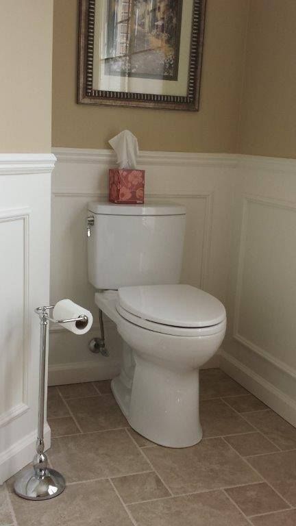 A person uses a red rubber plunger in a stainless steel sink while water runs from the faucet.