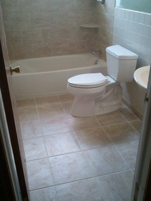 A gloved hand uses a red and yellow screwdriver to adjust the screw on a dual electrical wall outlet.