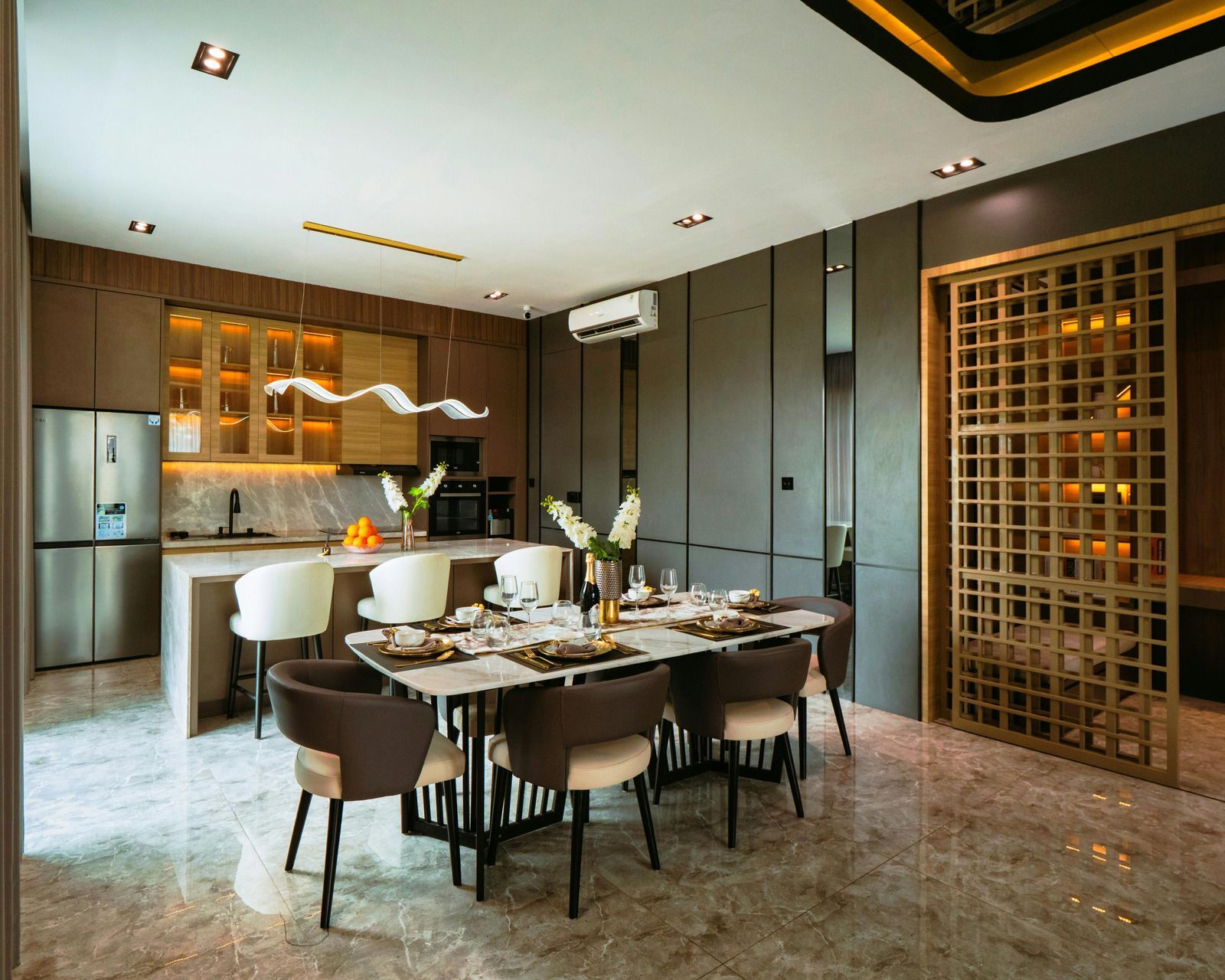 A modern dining room and kitchen featuring a stone table, brown and cream chairs, wooden cabinetry, and a grid partition.