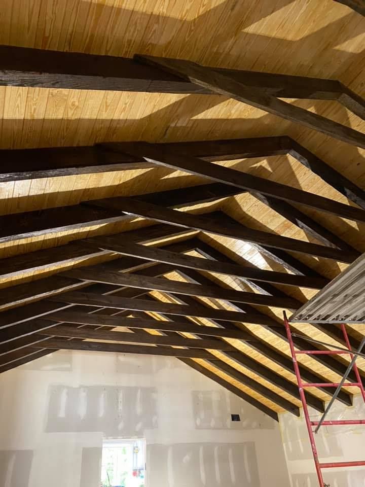Wooden ceiling with dark beams, light wood panels, and a red ladder.