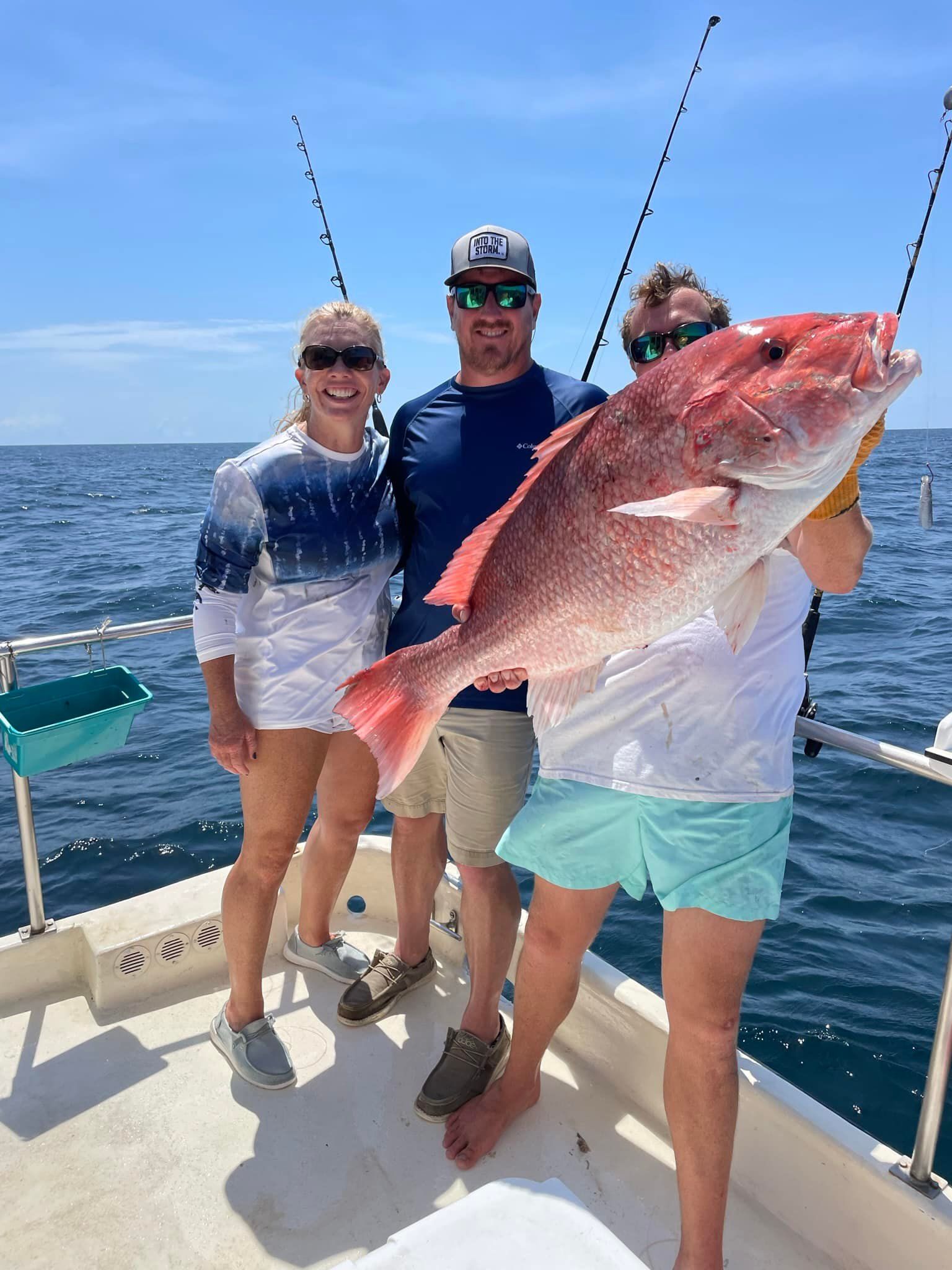 A group of people are standing on a boat holding a large fish.