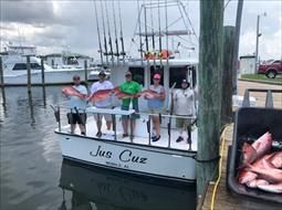 A group of people are standing on a boat holding fish.