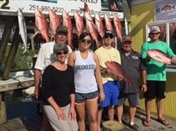 A group of people are standing next to each other holding fish.