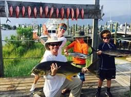 A man and two boys are holding a large fish on a dock.