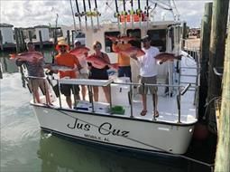 A group of people are standing on a boat holding fish.