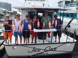 A group of people are standing on a boat holding fish.
