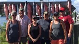 A group of people are posing for a picture in front of a display of fish.