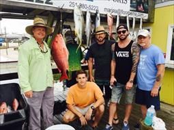 A group of men are posing for a picture with their catch of fish.