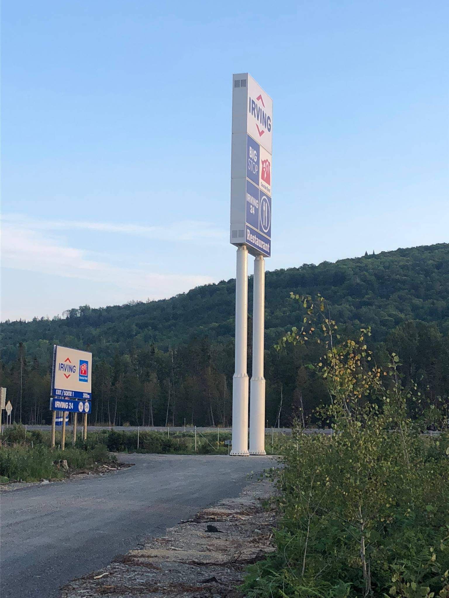 Un panneau de station-service est posé sur le bord d’une route.