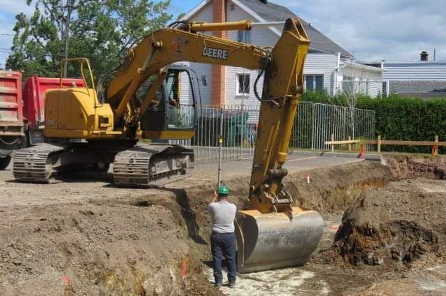 Un homme se tient devant une grosse pelle jaune.