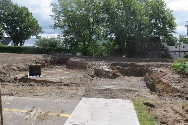 Un chantier de construction avec beaucoup de terre et des arbres en arrière-plan.