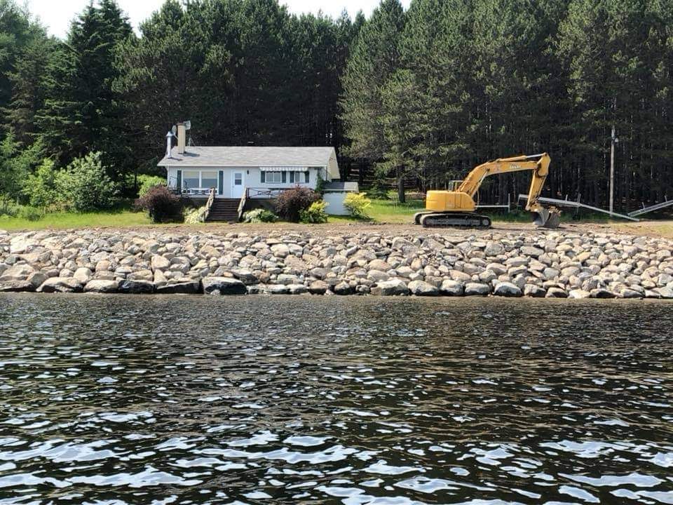 Une maison est située au bord d’un lac à côté d’un grand plan d’eau.