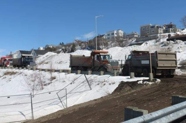 Une rangée de camions à benne basculante sont garés sur une colline enneigée