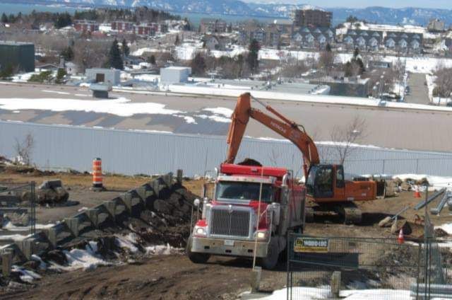 Un camion-benne est chargé de terre par une excavatrice.