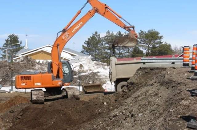 Une excavatrice Hitachi charge de la terre dans un camion-benne