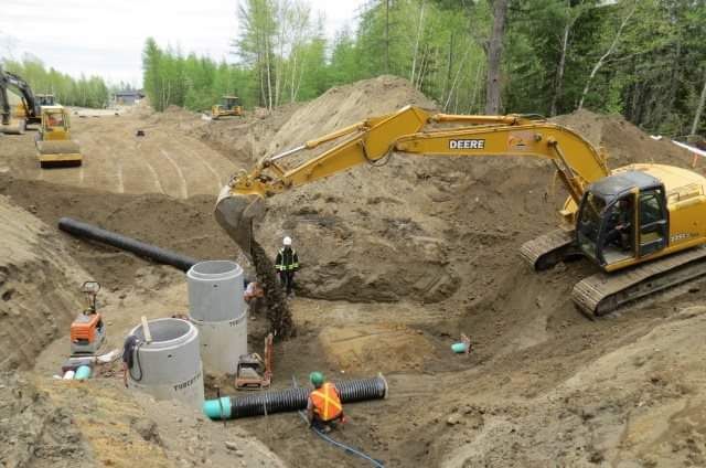 Une excavatrice jaune creuse un trou dans la terre.