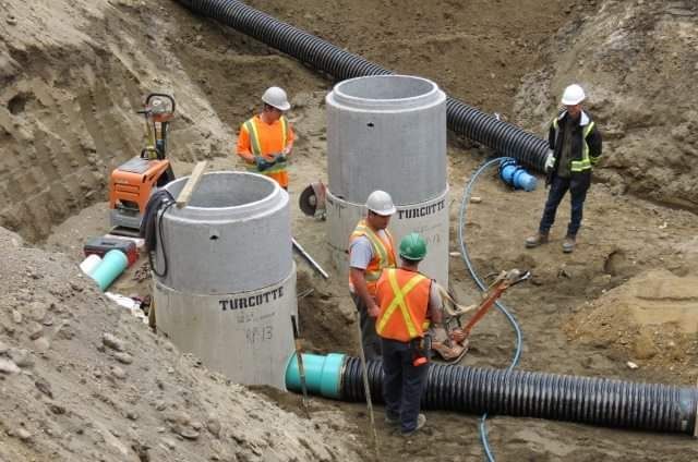 Un groupe d'ouvriers du bâtiment travaillent dans une fosse à terre.