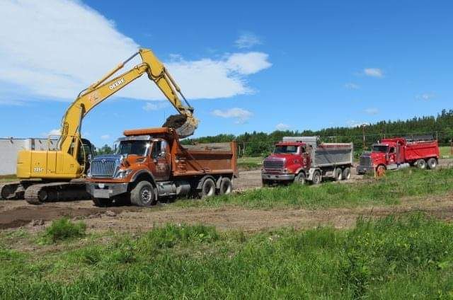 Une excavatrice jaune charge de la terre dans un camion-benne.