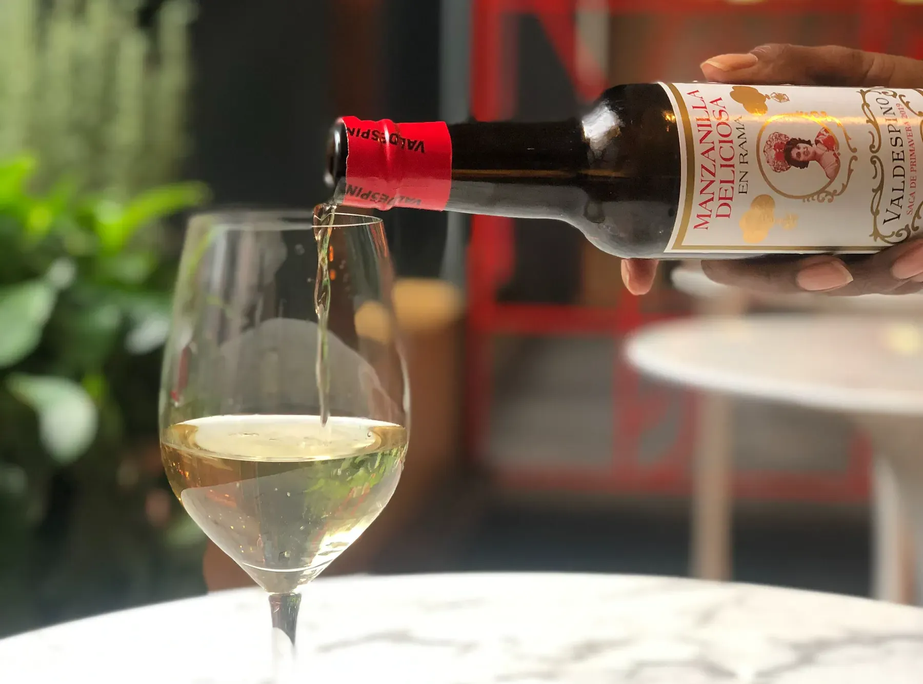 A person is pouring wine into a glass on a table in Jerez