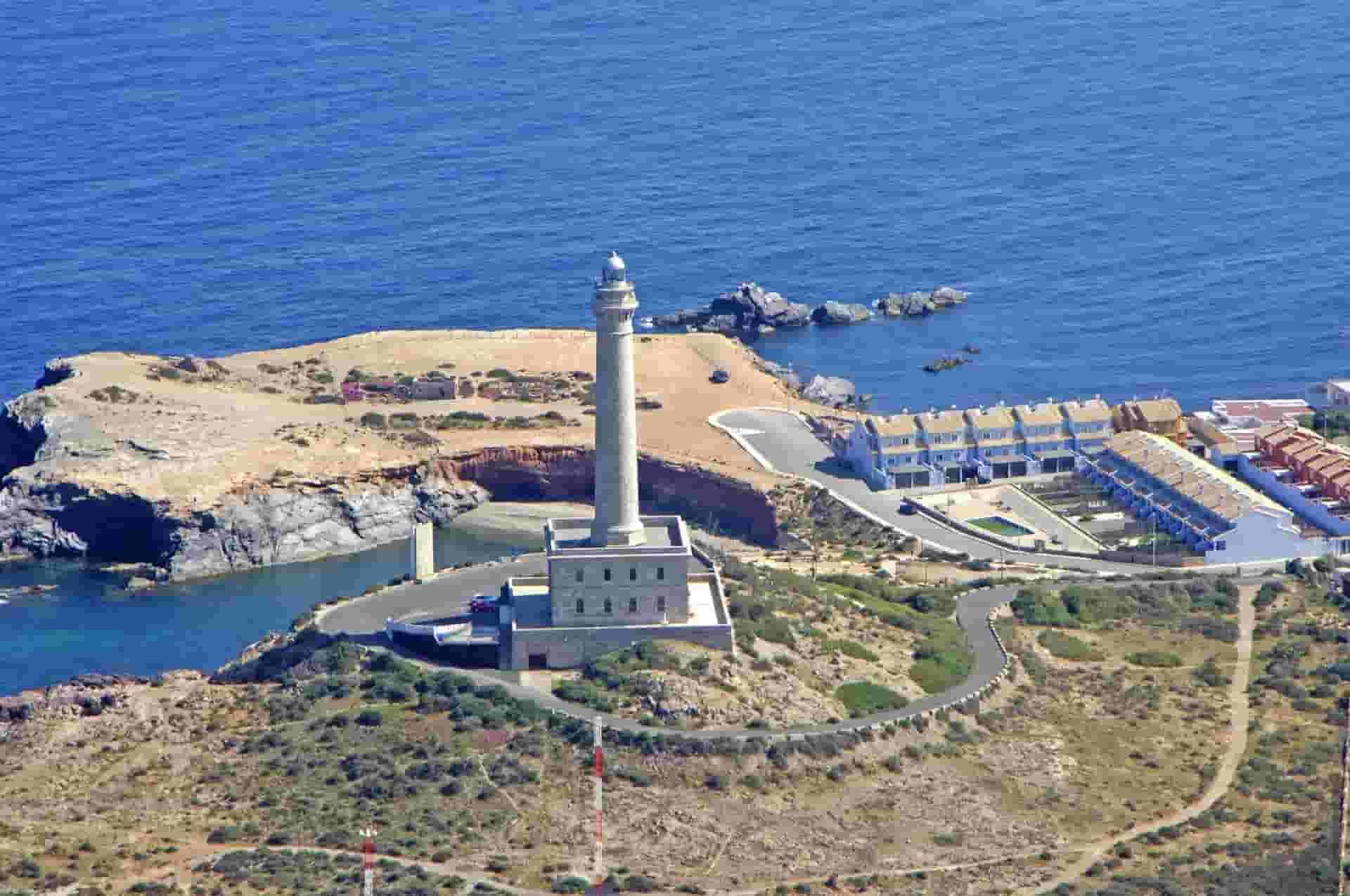 An aerial view of a lighthouse on a small island in the middle of the ocean