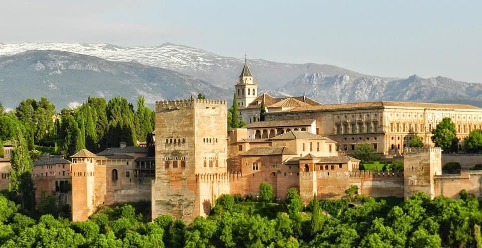 Alhambra building with arches and a pond in front of it