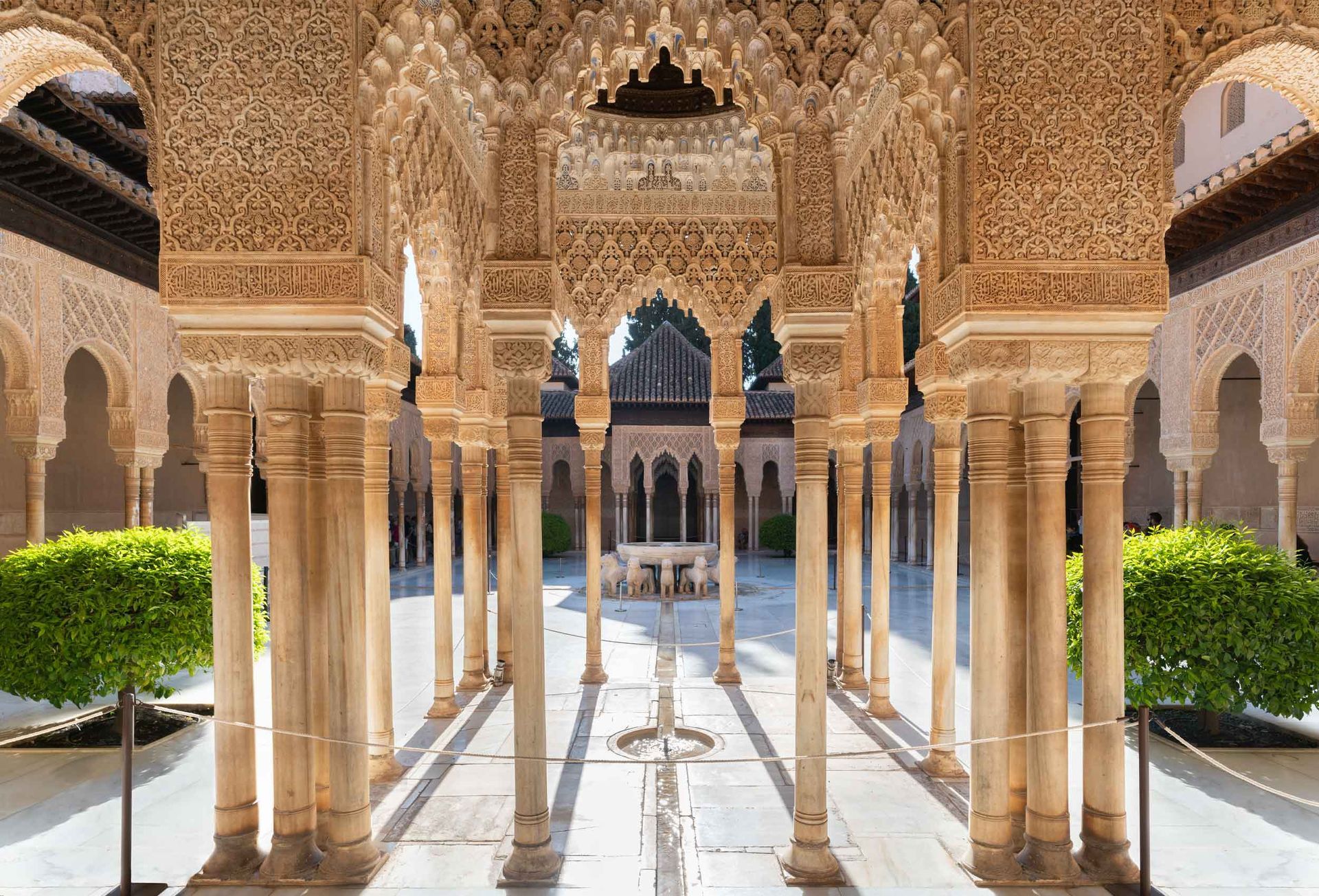 Alhambra courtyard filled with columns and arches with a fountain in the middle.