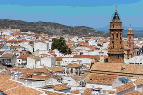 A castle in Antequera is sitting on top of a hill surrounded by trees.