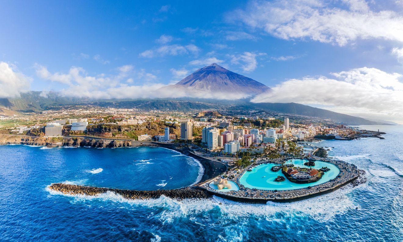 An aerial view of Tenerife in the middle of the ocean with a volcano in the background.